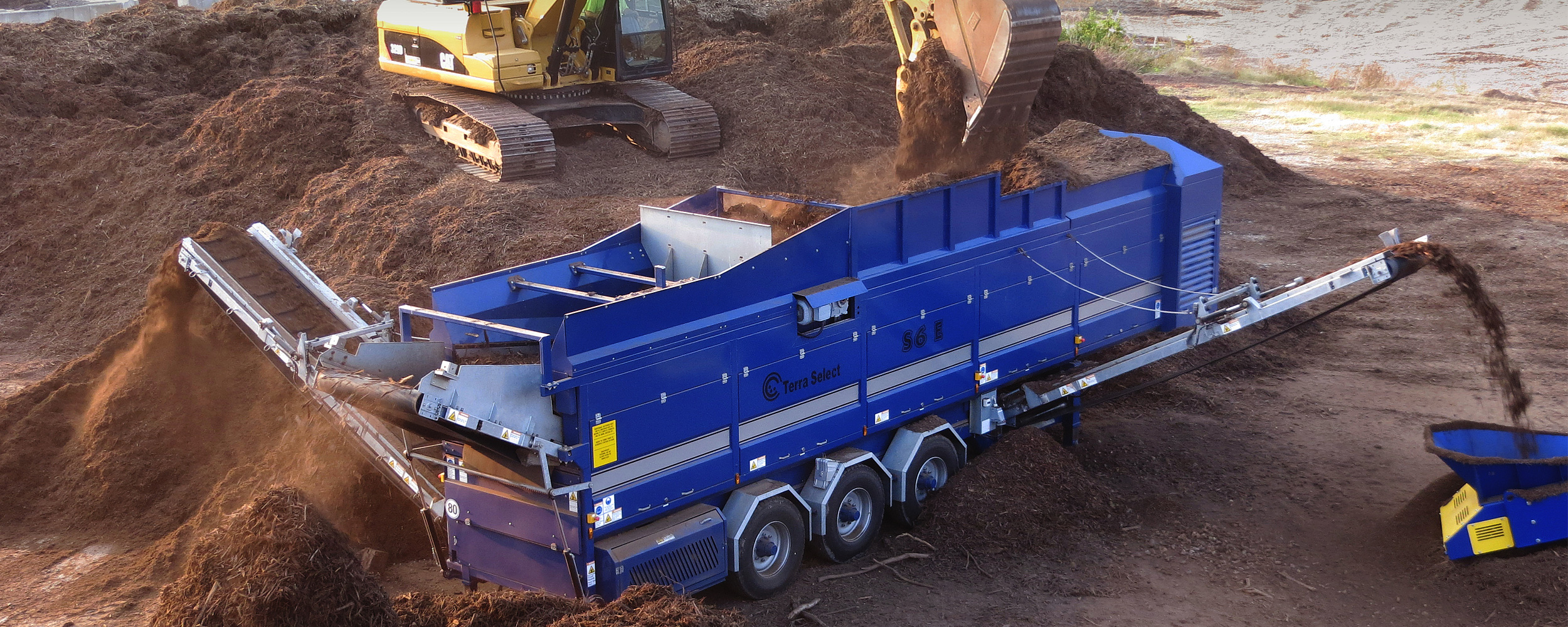 excavator loading material into screener